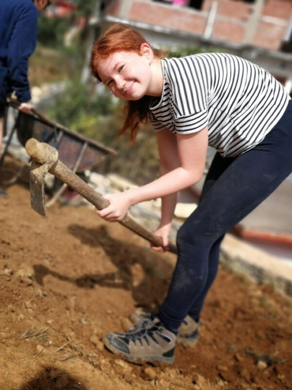 A student digging at a community project on a learning service journey