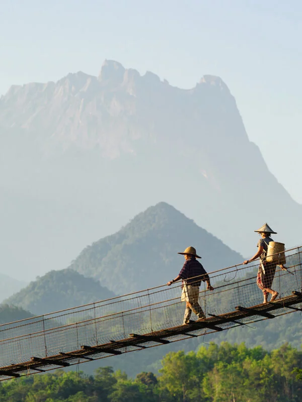 Locals walking over a suspension bridge in the Borneo jungle