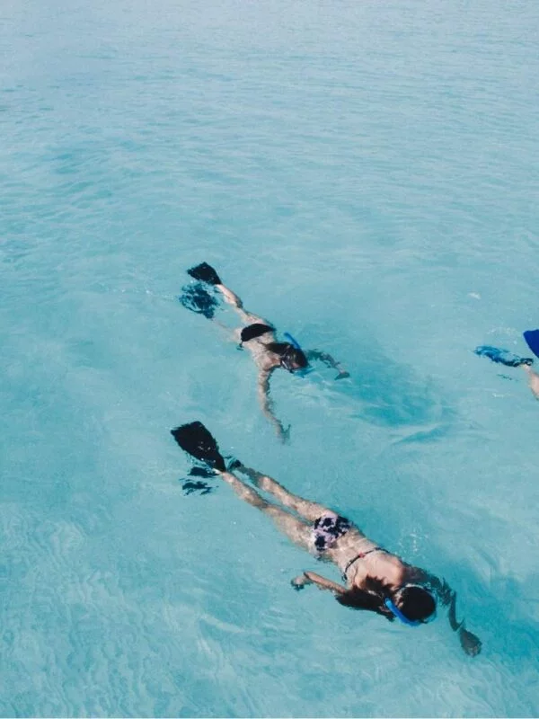 3 girls snorkelling in clear blue water on a school expedition